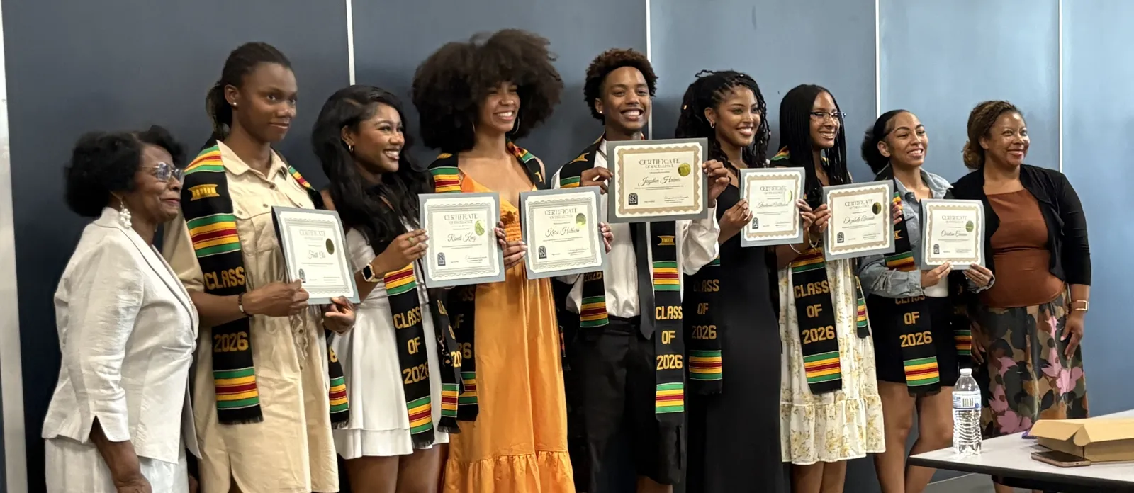 Olinga with Class of 2026 graduates holding certificates of excellence